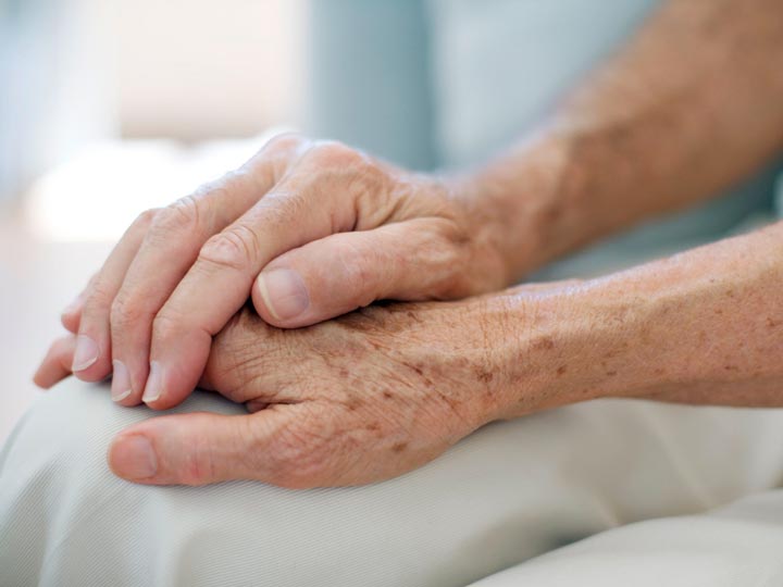 Hand einer Frau liegt auf der Hand einer Seniorin