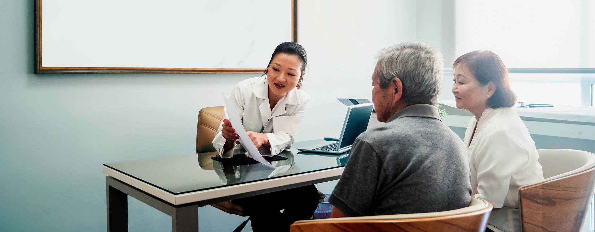 Eine Ärztin erklärt in ihrem Büro einem älteren Paar mögliche Therapieoptionen.