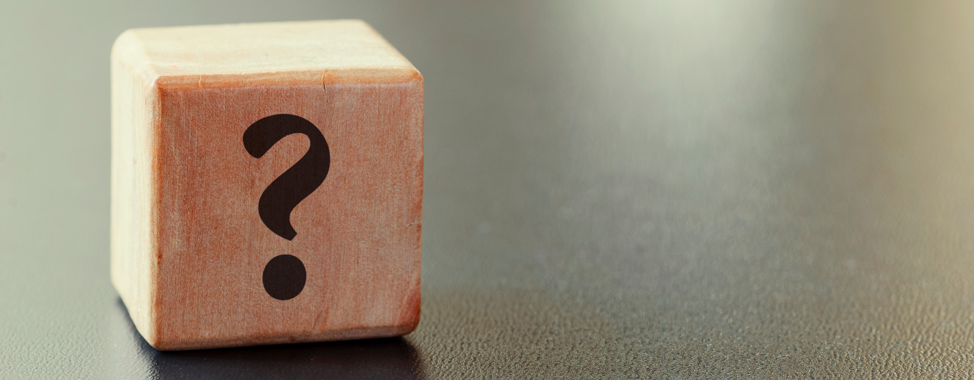 novartis-klinische-forschung-gut-informiert-gesundheitswissen-seltenen-krankheiten Ein Holzwürfel auf dem ein Fragezeichen ist vor neutralem Hintergrund.