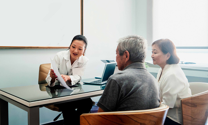 Ärztin erklärt älterem Paar Ergebnisse in einem Büro
