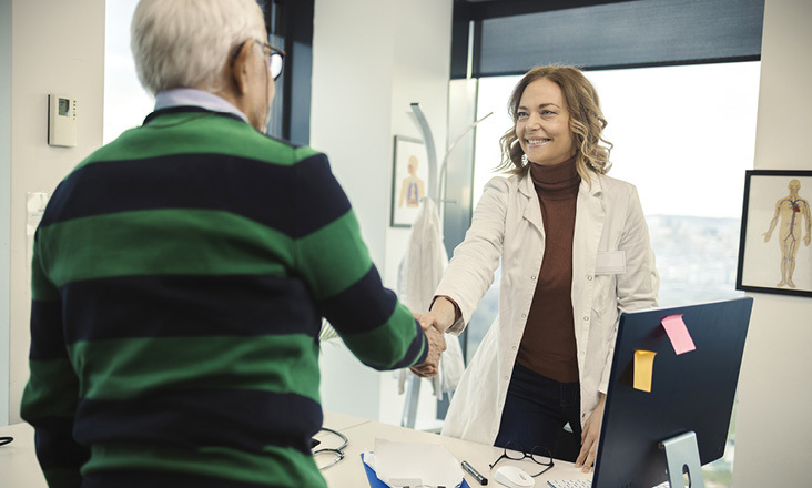 Ärztin schüttelt Patient Hand in einem Büro
