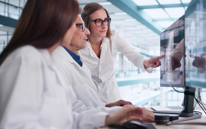 Drei Forschende analysieren gemeinsam Daten auf einem Bildschirm.